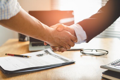blog_everythingyouneedtoknowaboutmoving_image3 Two men shake hands over a desk