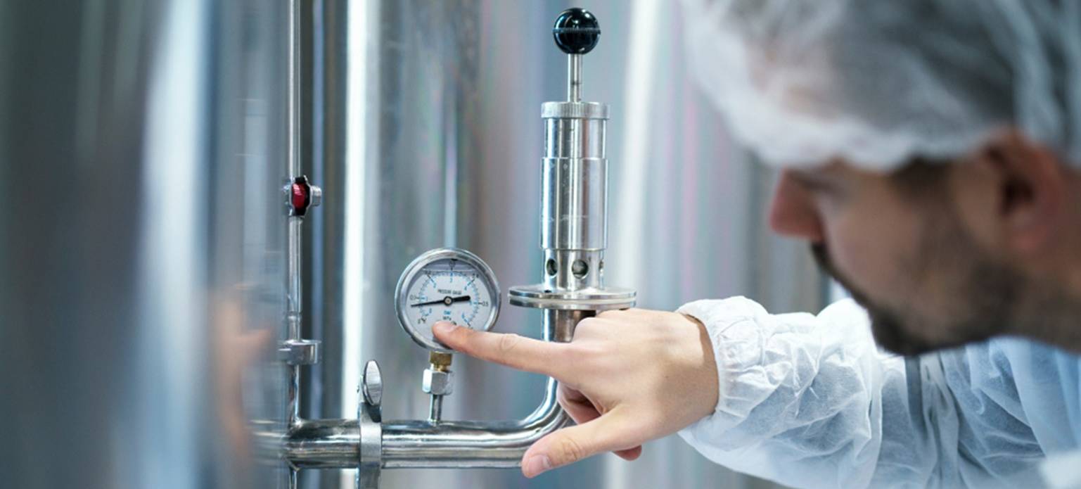 A man inspects a pressure gauge in a factory