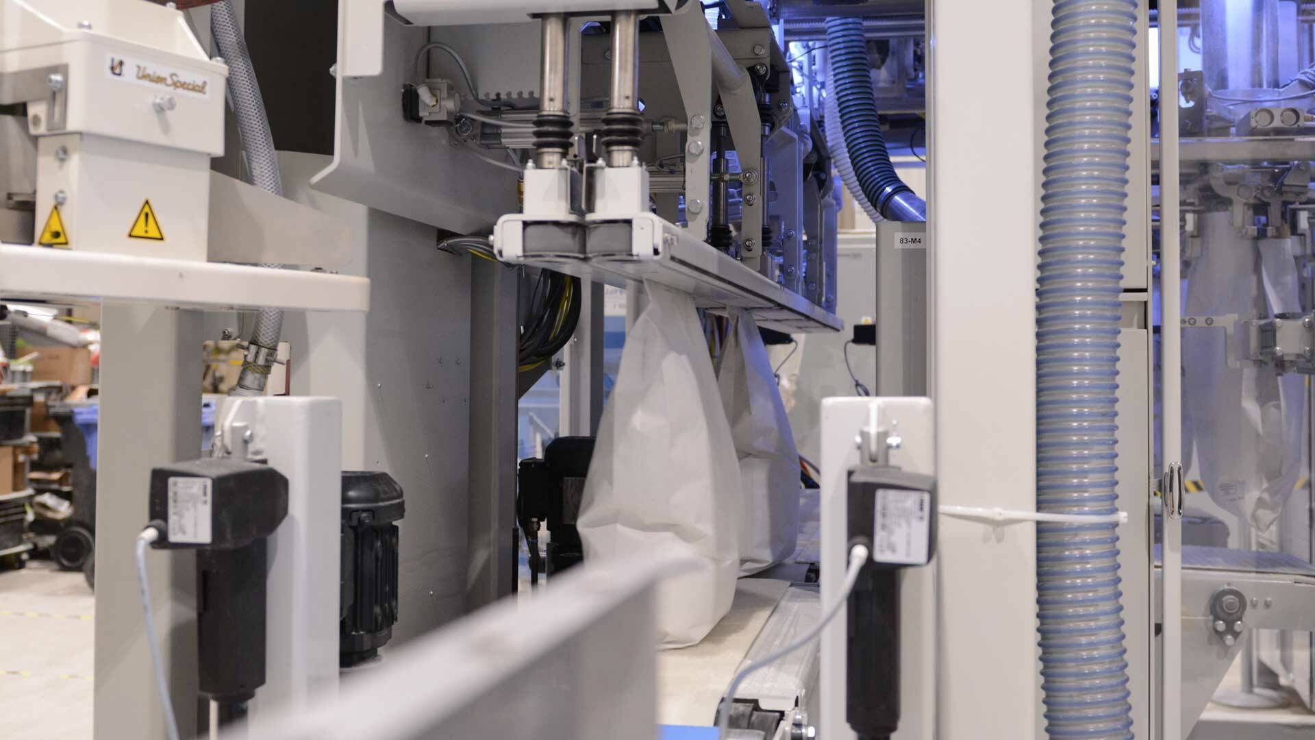 blog-high-precision-open-mouth-baggers-video-splashimage Open mouth bag filled with material being processed in the bag sealer