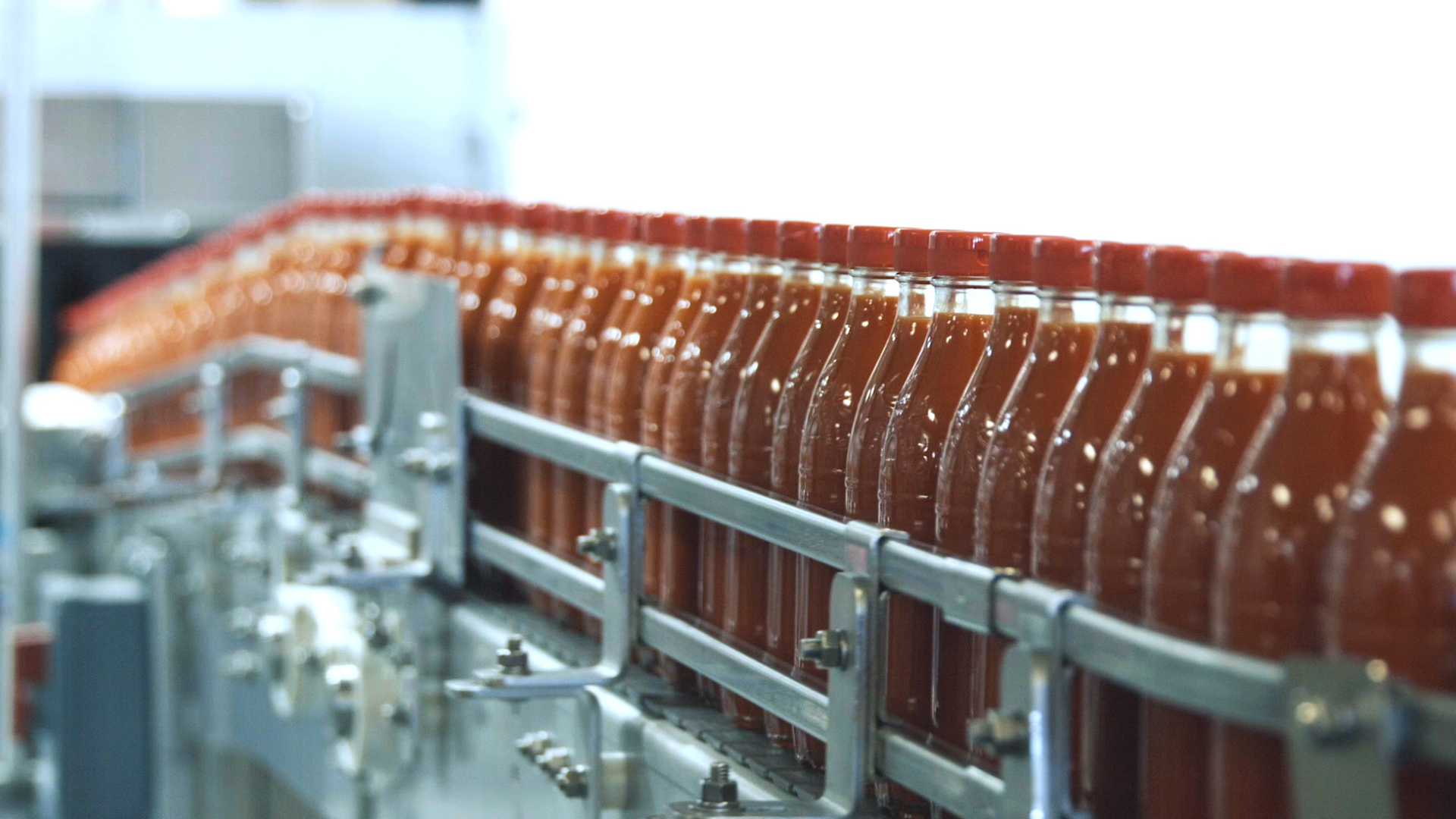 Hot sauce bottles in packaging on a production line, illustrating automated primary and secondary food packaging