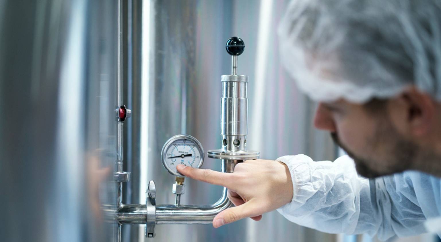 A man inspects a pressure gauge in a factory