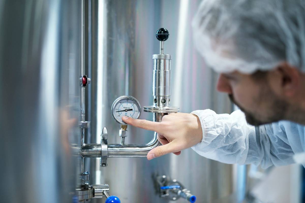 A man inspects a pressure gauge in a factory