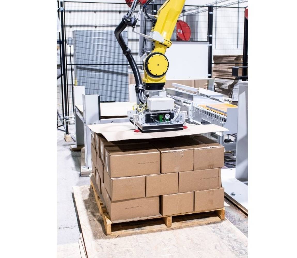 Robotic palletizer placing a slip sheet on a pallet