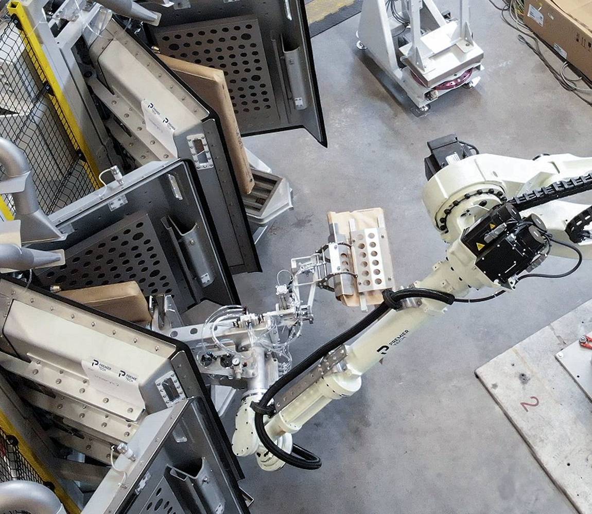 A robot removes a filled valve bag from a vacuum packer