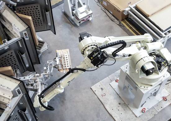 A robot removes a filled valve bag from a vacuum packer